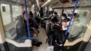 Orang-orang yang sebagian besar mengenakan masker duduk di Tube menuju Bandara Heathrow, London, Inggris, Senin (29/11/2021). Kasus ketiga COVID-19 varian Omicron dikonfirmasi pada Minggu kemarin oleh Badan Keamanan Kesehatan Inggris. (AP Photo/Frank Augstein)