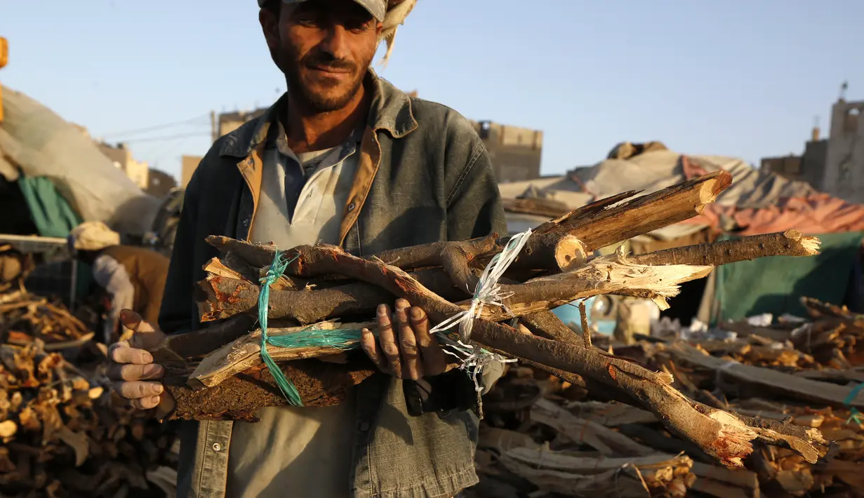 Seorang pria membawa tumpukan kayu di sebuah pasar di Sanaa, Yaman, pada 5 November 2020. Penduduk Yaman beralih menggunakan kayu untuk memasak karena kekurangan pasokan bahan bakar. (Xinhua/Mohammed Mohammed)