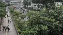 Pekerja melintasi trotoar saat jam pulang kantor di kawasan Sudirman, Jakarta, Senin (14/9/2020). Selama PSBB, Pemprov DKI Jakarta mewajibkan perusahaan nonesensial untuk membatasi 25 persen dari total pekerja yang bekerja di kantor guna memutus penyebaran Covid-19. (merdeka.com/Iqbal S. Nugroho)