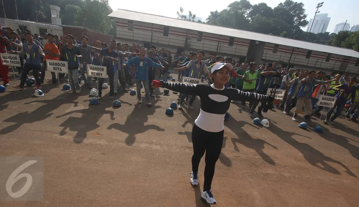 Pekerja renovasi Stadion Utama GBK mengikuti instruktur senam sebelum beraktivitas di kawasan Senayan, Jakarta, Jumat (17/3). Senam dilakukan untuk menjaga kebugaran pekerja yang rutin diadakan setiap Jumat pagi. (Liputan6.com/Immanuel Antonius)