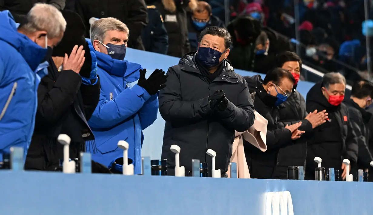 Presiden Komite Olimpiade Internasional (IOC) Thomas Bach (kiri) dan Presiden China Xi Jinping (kanan) bertepuk tangan saat upacara pembukaan Olimpiade Musim Dingin Beijing 2022, di Stadion Nasional, yang dikenal sebagai Stadion Bird's Nest, Beijing, pada 4 Februari 2022. (AFP/Pool/Anthony Wallace)