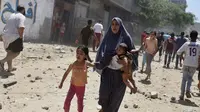 Wanita Palestina berlari bersama anak-anaknya saat terjadi serangan udara Israel terhadap sebuah rumah di kota Gaza, Rabu (9/7/14). (REUTERS/Majdi Fathi)
