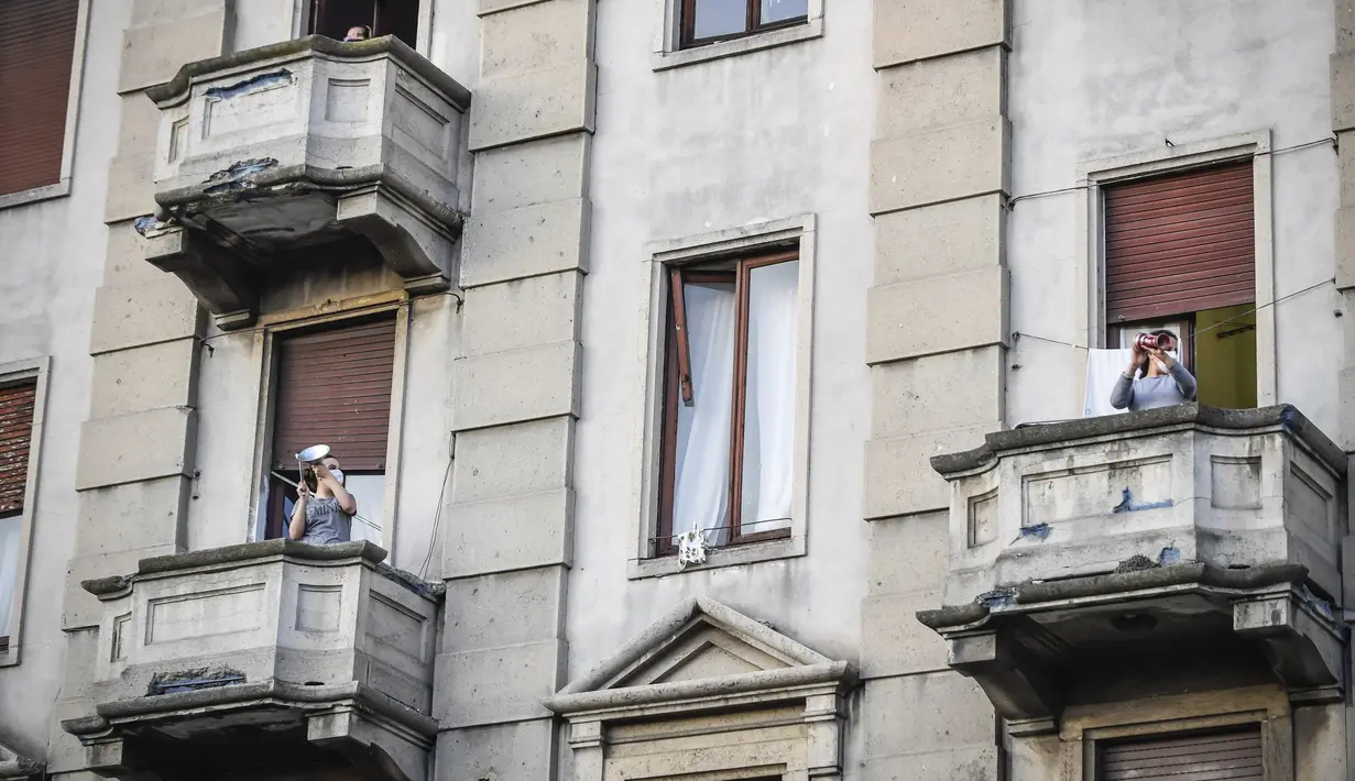 Warga berada di balkon untuk bermain dan bernyanyi selama flash mob untuk menyatukan orang-orang dan mengatasi keadaan darurat Covid-19 di Roma (13/3/2020).  (Claudio Furlan/LaPresse via AP)