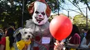 Seorang pria mengenakan kostum badut berpose dengan anjingnya saat Parade Halloween Anjing Tahunan di Tompkins, New York (21/10). Pemilik anjing juga ikut memakai kostum aneh untuk mengikuti parade ini. (AFP Photo/Timothy A. Clary)