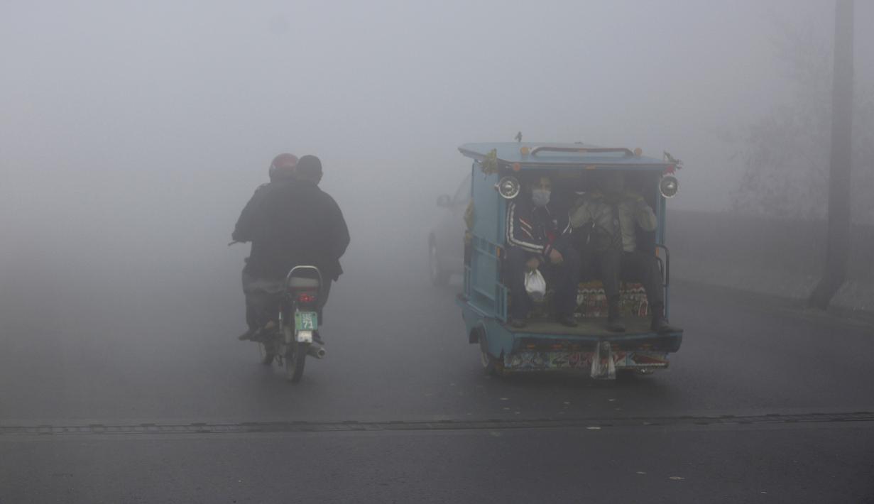 Becak dan pengendara sepeda motor melaju di jalan saat kabut tebal mengurangi jarak pandang di Lahore, Pakistan, Selasa (30/11/2021). Lahore secara konsisten menempati peringkat sebagai salah satu kota terburuk di dunia untuk polusi udara. (AP Photo/K.M. Chaudary)