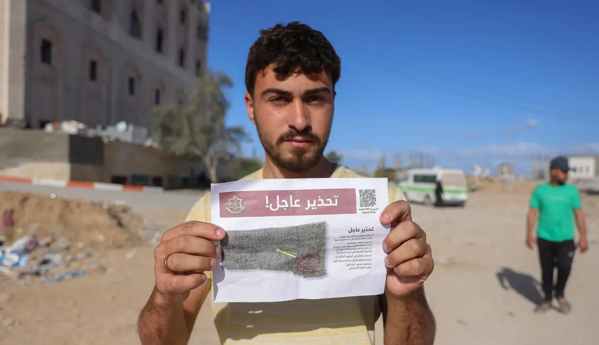 Seorang pria Palestina menunjukkan salah satu selebaran yang disebarkan oleh tentara Israel di Beit Hanun, Jalur Gaza utara pada 19 Maret 2025. (BASHAR TALEB/AFP)