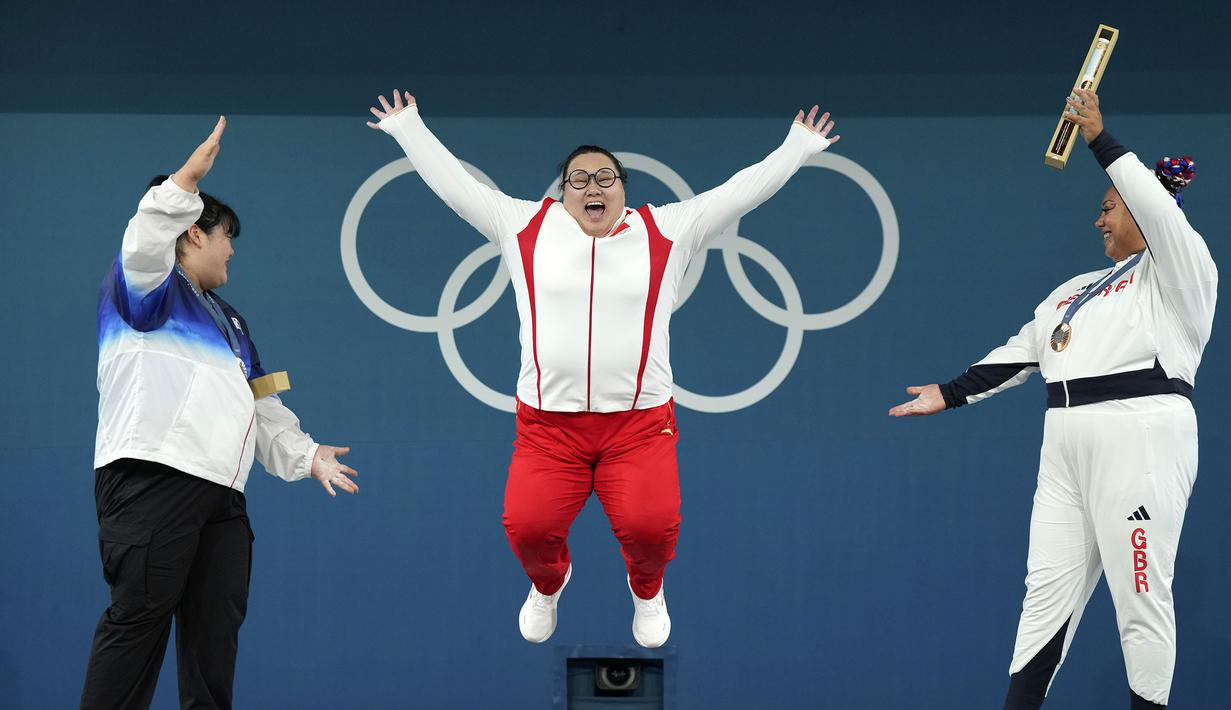 Lifter China, Li Wenwen (tengah) melakukan selebrasi di atas podium setelah memastikan diri meraih medali emas cabang olahraga angkat besi +81kg putri Olimpiade Paris 2024 di South Paris Arena, Paris, Prancis, Sabtu (11/08/2024). (AP Photo/Kin Cheung)