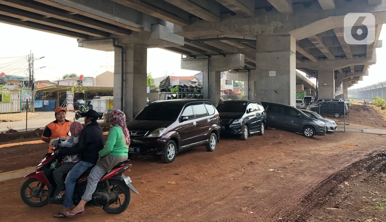Warga berbincang dekat mobil yang parkir di kolong jalan tol Becakayu di kawasan Cipinang Muara, Jakarta, Jumat (13/3/2020). Minimnya lahan parkir membuat sebagian orang tetap memarkirkan kendaraannya di kolong tol tersebut, meskipun telah terpampang larangan parkir. (Liputan6.com/Immanuel Antonius)