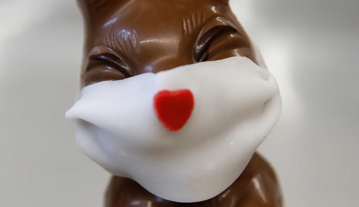 Cokelat paskah berbentuk kelinci yang mengenakan masker di toko roti Baeckerei Bohnenblust di Bern, Swiss, Jumat (27/3/2020). Cokelat berbentuk kelinci dengan masker berwarna putih dari tepung gula ini dibuat di tengah pandemi virus corona yang sedang merebak di seluruh dunia. (STEFAN WERMUTH/AFP)
