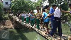 Sejumlah pelajar menyeberangi Kali Angke melewati jembatan rapuh di Kampung Cantiga, Petir, Cipondoh, Tangerang, Rabu (2/9/2015). Jembatan berusia lima tahun tersebut menghubungkan Cipondoh dan Kembangan, Jakarta. (Liputan6.com/Gempur M Surya)
