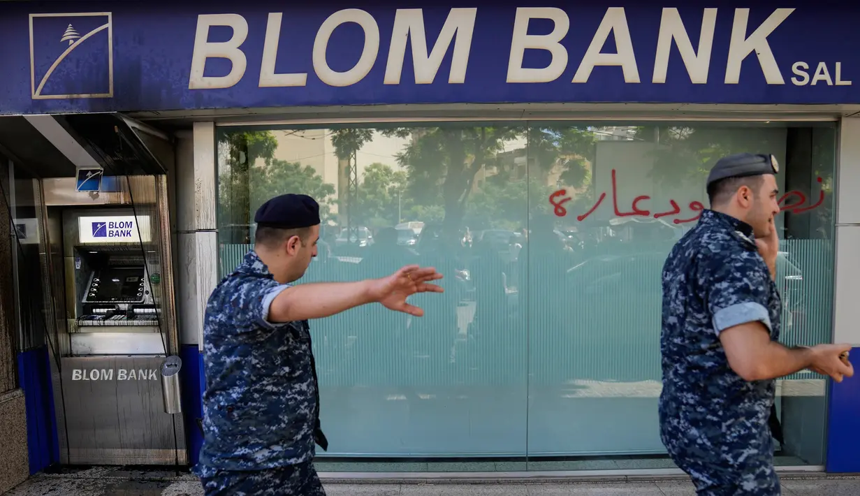 Polisi Lebanon lewat di sebelah bank yang diserang oleh para nasabah, Beirut, Lebanon, Rabu (14/9/2022). Bank-bank Lebanon yang kekurangan uang sejak 2019 telah memberlakukan batasan ketat pada penarikan mata uang asing, mengikat tabungan jutaan orang. (AP Photo/Hussein Malla)