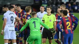 Para pemain Barcelona memprotes keputusan wasit Adrian Cordero Vega (tengah) yang memberikan hadiah penalti kepada SD Huesca dalam laga lanjutan Liga Spanyol 2020/2021 pekan ke-27 di Camp Nou Stadium, Barcelona, Senin (15/3/2021). Barcelona menang 4-1 atas SD Huesca. (AFP/Lluis Gene)