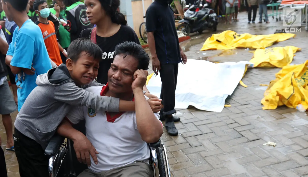 Seorang anak menangis memeluk ayahnya pasca terjadinya gelombang di Puskesmas Carita, Banten, Minggu (23/12). BNPB mencatat ratusan orang meninggal dunia dan ratusan luka-luka. (Liputan6.com/Angga Yuniar)