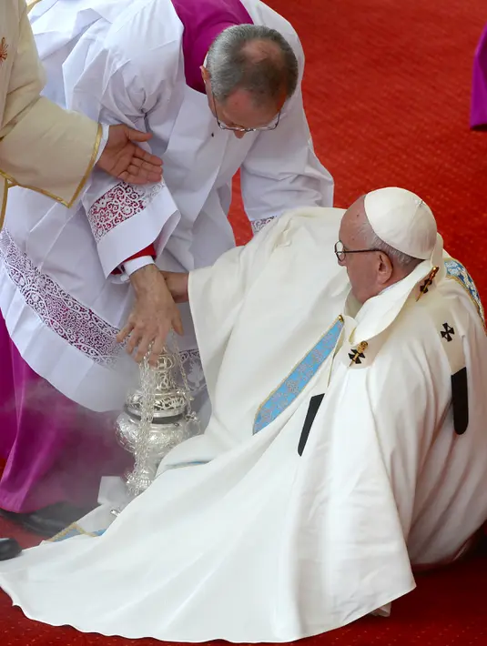 Seorang imam membantu Paus Fransiskus berdiri usai terjatuh saat berjalan menuju altar terbuka di biara Jasna Gora, Polandia, Kamis (28/7). Kunjungan Paus Fransiskus ke Polandia untuk menghadiri perayaan World Youth Day. (FILIPPO MONTEFORTE/AFP)