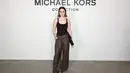 <p>Kaitlyn Dever mengenakan chocolate viscose bodysuit dengan glen plaid wool slouch trousers, menciptakan harmoni antara maskulin dan feminin. [Dok/Michael Kors].</p>