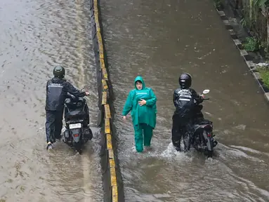 Pengendara dan pejalan kaki melintasi banjir yang menggenangi Jalan Jembatan Tiga Raya, Jakarta Utara, Senin (12/1/2026). Hujan deras yang mengguyur Jakarta menyebabkan banjir di sejumlah wilayah pada Senin (12/1/2026). (merdeka.com/Arie Basuki)