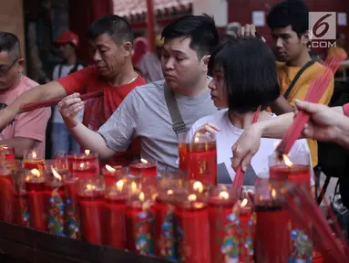 Warga keturunan Tionghoa menyalakan lilin saat bersembahyang Imlek 2569 di Vihara Dharma Bhakti, Petak Sembilan, Jakarta Barat, Jumat (16/2). Imlek 2569 jatuh pada shio anjing atau bisa disebut sebagai tahun anjing. (Liputan6.com/Arya Manggala)