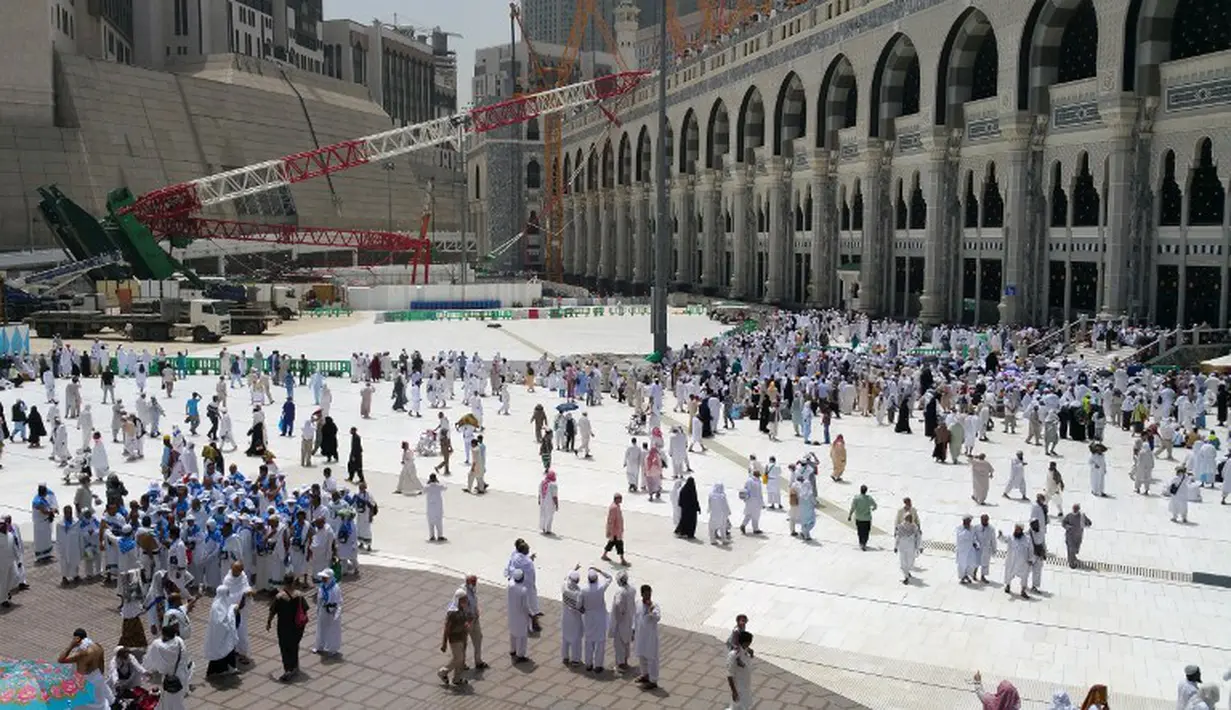 Ribuan umat muslim yang sedang menunaikan ibadah haji berjalan melintasi crane yang roboh di Masjidil  Haram, Mekah,  Arab Saudi (9/12/2015). Sebanyak 107 calon jemaah haji meninggal dunia akibat crane jatuh karena cuaca buruk. (REUTERS/Mohamed Al Hwaity)