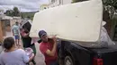 Orang-orang mengarungi air saat mereka memindahkan barang-barang dari rumah mereka yang terendam banjir di negara bagian Minas Gerais di kotamadya Juatuba, Brasil (10/1/2022). Hujan deras yang turun dalam beberapa hari terakhir di bagian tenggara negara itu membuat banjir besar. (AFP/Douglas Magno)