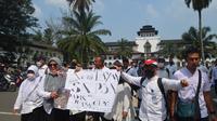 Sejumlah guru honorer membentang poster aspirasi saat aksi Catwalk di depan Gedung Sate, Kota Bandung, Senin, 25 Juli 2022. Dikdik Ripaldi/Liputan6.com