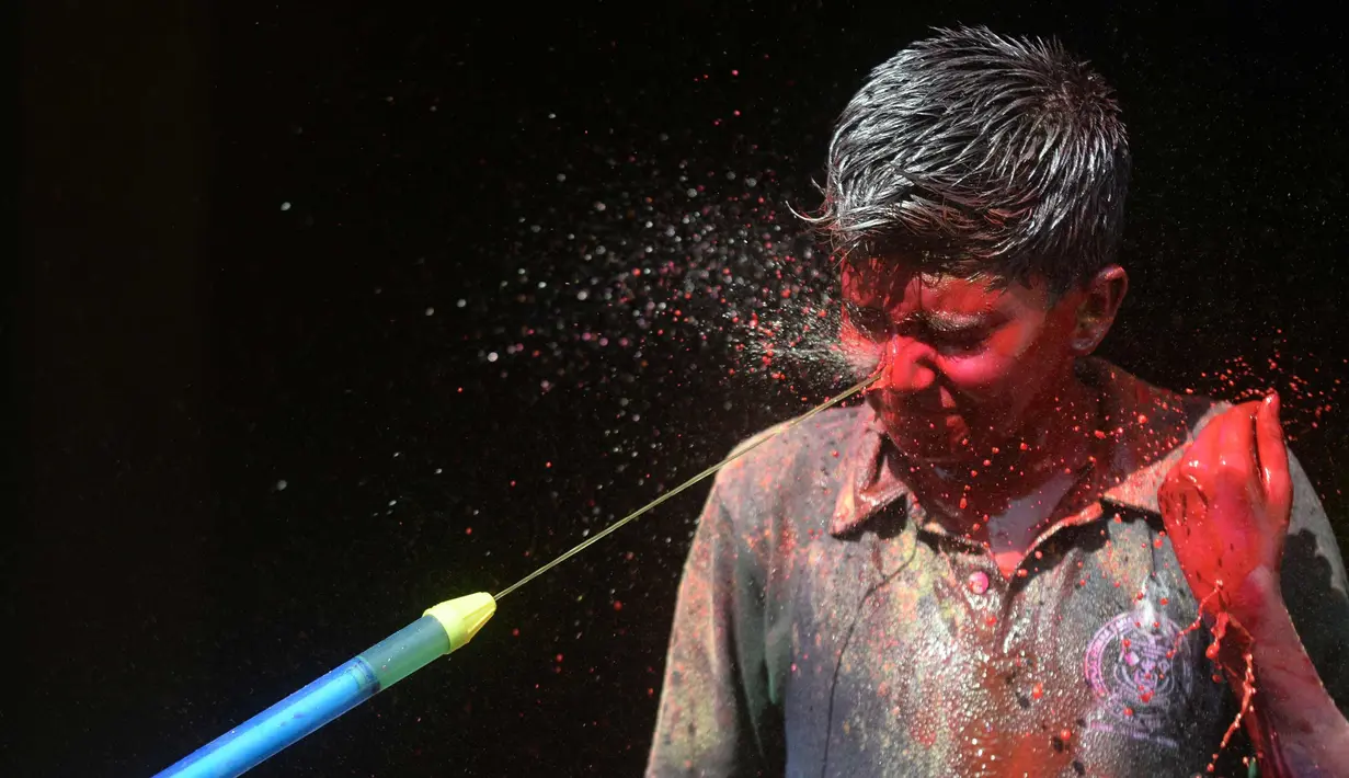 Seorang anak India terkena semprotan air berwarna selama festival Holi di Chennai (2/3). Holi, festival musim semi hindu di India yang diadakan 2 Maret tahun ini pada akhir musim dingin pada bulan purnama pertama kalender lunar. (AFP Photo/Arun Sankar)