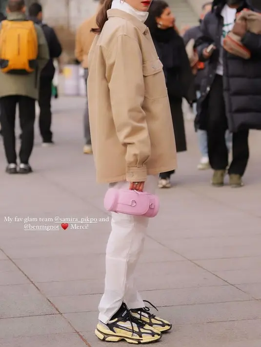 Jaket tersebut serasi dengan celana panjang model training. Dipadukan sneaker hitam putih, sambil membawa mini bag pink.  [@enzystoria]