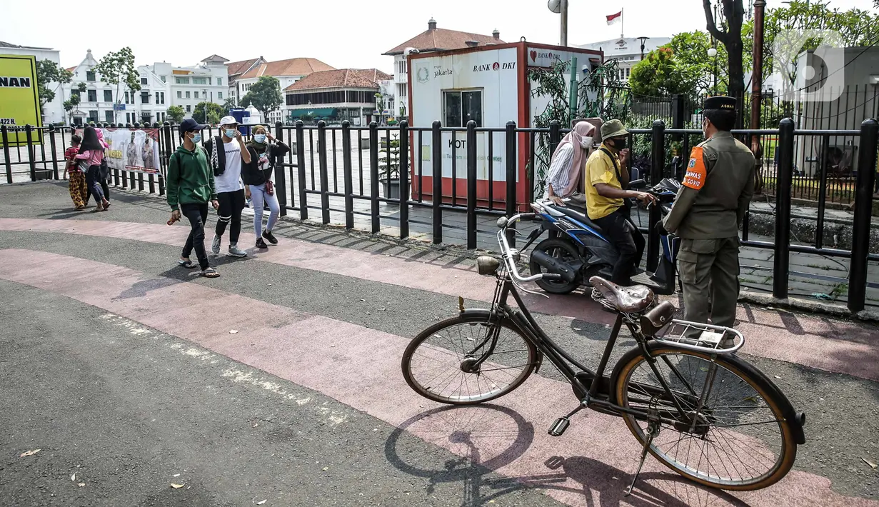 Petugas Satpol PP berjaga di depan kawasan wisata Kota Tua, Jakarta, Sabtu (15/5/2021). Pemerintah Provinsi DKI Jakarta menutup kawasan wisata Kota Tua hingga 16 Mei 2021. (Liputan6.com/Faizal Fanani)