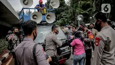 Petugas kepolisian beradu argumen saat memberhentikan mobil komando aksi di sekitar Gedung DPR, Jakarta, Jumat (14/8/2020). Polda Metro Jaya melarang adanya unjuk rasa di depan Gedung DPR/MPR yang bertepatan dengan sidang tahunan. (Liputan6.com/Faizal Fanani)