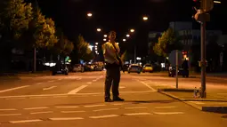Seorang polisi berjaga di sebuah jalan di dekat pusat perbelanjaan Olympia Einkaufzentrum (OEZ) di Munich, Jerman (22/7). Penembakan ini hanya berselang tiga hari setelah terjadinya penyerangan di kereta api Jerman. (AFP PHOTO/Christof Stache)