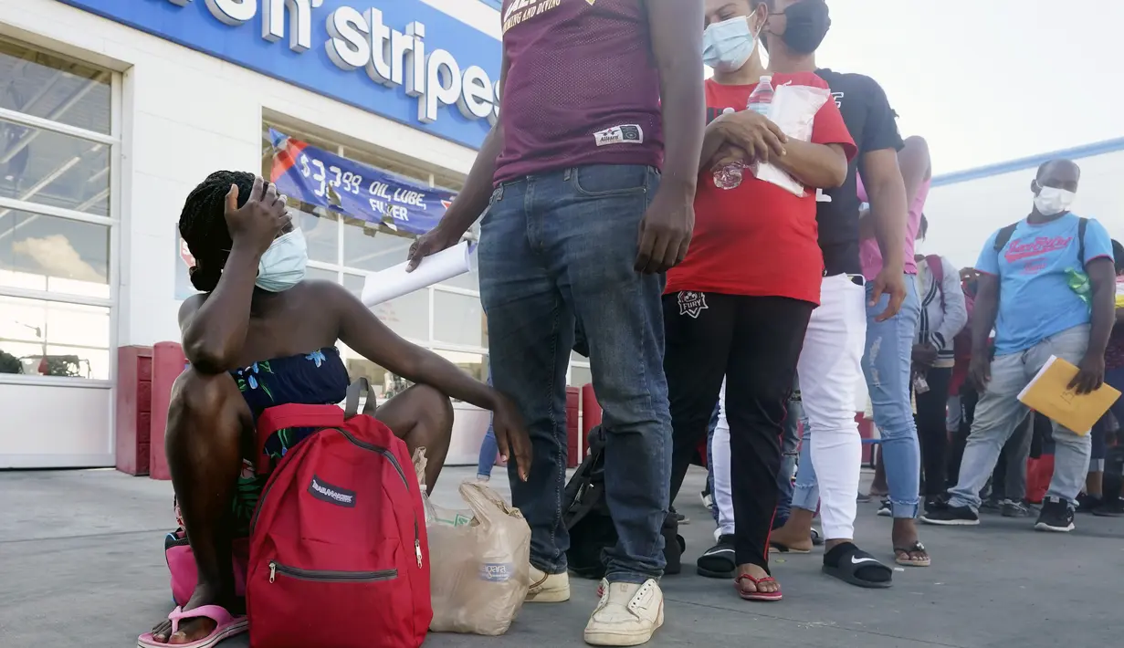Migran, sebagian besar dari Haiti, menunggu bus setelah mereka diproses dan dibebaskan setelah menghabiskan waktu di kamp darurat dekat Jembatan Internasional di Del Rio, Texas, Minggu (19/9/2021). (AP Photo/Eric Gay)