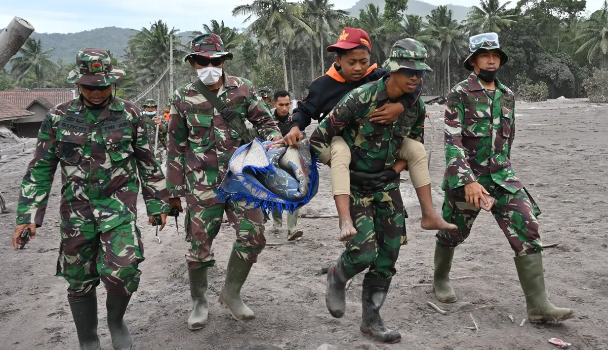Tim SAR gabungan menggendong warga selama operasi pencarian dan penyelamatan korban erupsi Gunung Semeru di desa Sumberwuluh, Lumajang, Jawa Timur, Senin (6/12/2021). Berdasarkan laporan BNPB, jumlah korban meninggal sampai Minggu sore berjumlah 14 orang. (ADEK BERRY/AFP)