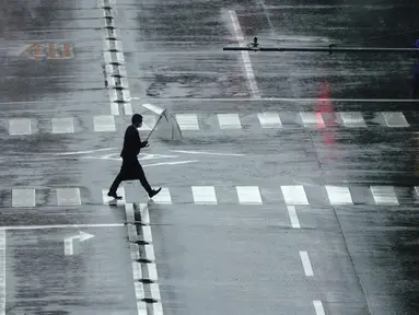 Seorang pria berjalan di tengah hujan yang dibawa oleh Topan Mindulle di Tokyo, Jepang, Jumat (1/10/2021). Topan Mindulle sedang bergerak di lepas pantai Jepang. (AP Photo/Eugene Hoshiko)