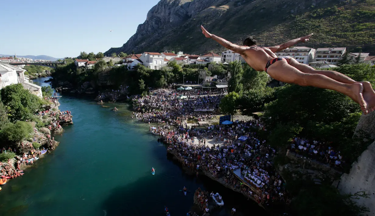 Peserta melakukan lompatan dari atas jembatan Mostar selama kompetisi menyelam tradisional ke 451 di Mostar, Bosnia, Minggu (30/7). Para peserta dari Bosnia dan negara-negara tetangga itu melakukan lompatan dari ketinggian 25 meter. (AP Photo/Amel Emric)