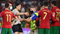 Petugas keamanan stadion menahan seorang penyusup lapangan setelah pertandingan sepak bola Grup F UEFA EURO 2020 antara Portugal melawan Prancis yang berlangsung di Puskas Arena, Budapest pada 23 Juni 2021. (AFP/Pool/Franck Fife)