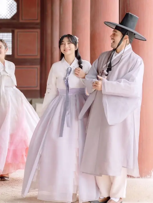 Ia mengenakan hanbok pastel putih ungu dengan rambut half ponytail berhiaskan untaian bunga [@hestipurwadinata]