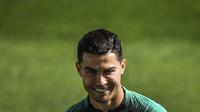 Penyerang Portugal, Cristiano Ronaldo tersenyum selama sesi pelatihan tim di stadion Algarve di Faro (13/11/2019). Portugal akan bertanding melawan Lithuania pada Grup B Kualifikasi Piala Eropa 2020 di Estádio Algarve. (AFP Photo/Patricia De Melo Moreira)
