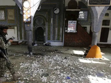 Seorang militan Houthi berjalan diantara reruntuhan sebuah masjid di Yaman, Kamis (24/9/2015). Sebuah ledakan terjadi di Masjid Balili di Sanaa, Yaman. Dikabarkan, 29 orang tewas dan puluhan terluka. (REUTERS/Khaled Abdullah)