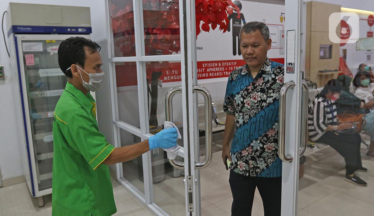 Petugas menggunakan sarung tangan dan kain untuk membukakan pintu di PMI DKI Jakarta, Jumat (20/3/2020). PMI DKI Jakarta memberlakukan disiplin saling menjaga jarak atau social distancing agar kegiatan donor darah tetap aman dan terhindar dari penularan COVID-19. (Liputan6.com/Herman Zakharia)