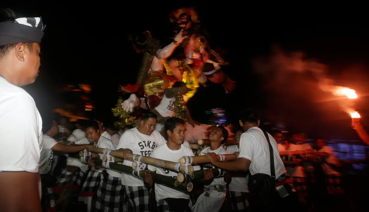 Pemuda mengarak Ogoh-Ogoh menjelang Hari Raya Nyepi Tahun Saka 1940 di Bali, Kamis (15/3). Ogoh-ogoh yang hadir dalam sosok Butha Kala dianggap umat Hindu Bali sebagai lambang keinsyafan manusia akan kekuatan alam semesta dan waktu. (AP/Firdia Lisnawati)