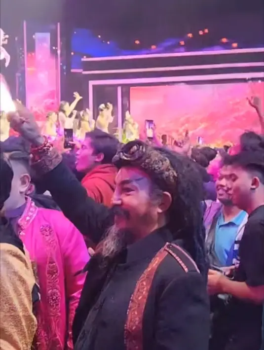 Dalam foto yang tersebar, Limbad terlihat berdiri di antara kerumunan penggemar JKT48. Pakaian hitam dengan aksen etnik serta sorban khas menghiasi penampilannya. Meski ramai, ia tidak ikut menyanyi, hanya bergoyang pelan menikmati irama lagu yang dibawakan. (Liputan6.com/IG/@limbadindonesia)