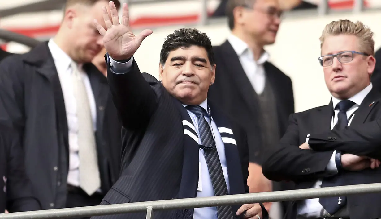 Diego Maradona melambaikan tangan kepada fans saat menyaksikan laga Totenham Hotspur melawan Liverpool di Wembley Stadium, London, (22/10/2017). (Adam DavyPA via AP)