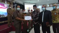Wakil Ketua Komisi X DPR Abdul Fikri Faqih menyerahkan piagam Dana Alokasi Khusus (DAK) untuk dinas perpustakaan di wilayah Sumatera Barat kepada Kepala Dinas Kearsipan dan Perpustakaan Provinsi Sumbar Wardarusmen. (Liputan6.com/ Ist)