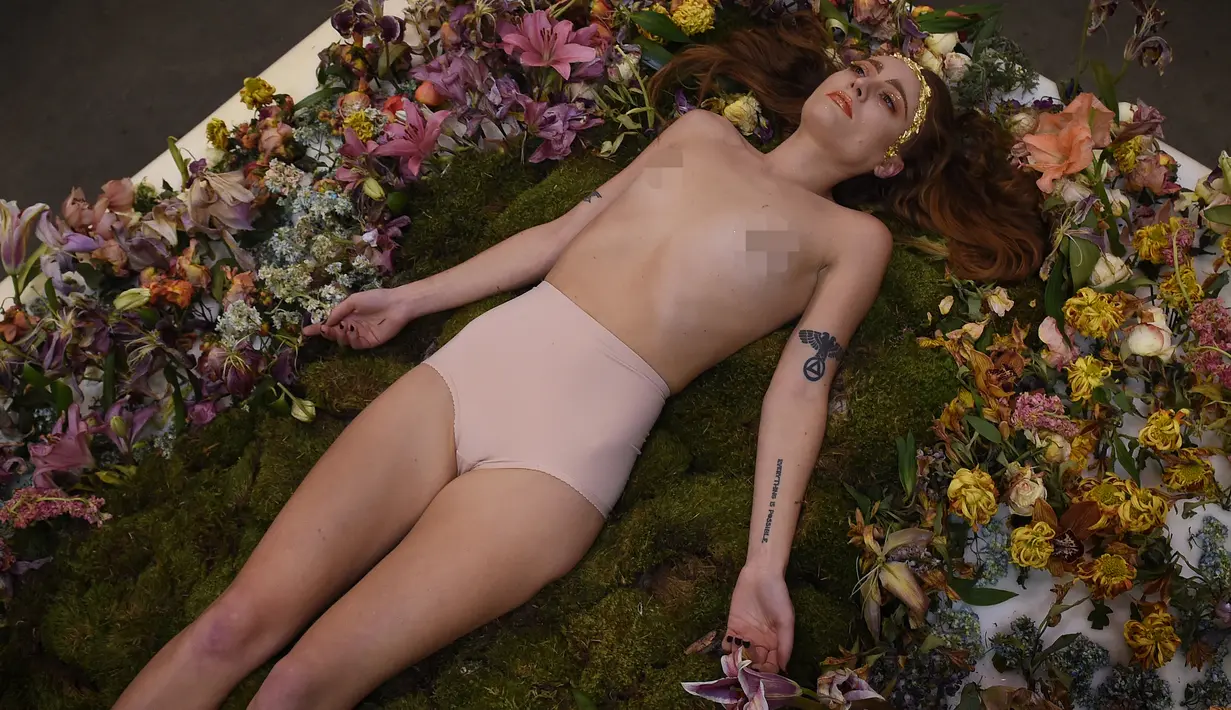Millie Brown, seorang seniman wanita dalam posisi tidur di atas karya seninya saat pameran berjudul 'Wilting Point' atau Titik Layu di LA Art Show, Los Angeles, Minggu (31/1). Brown akan bertahan selama 5 hari hanya meminum air. (Mark Ralston/AFP)