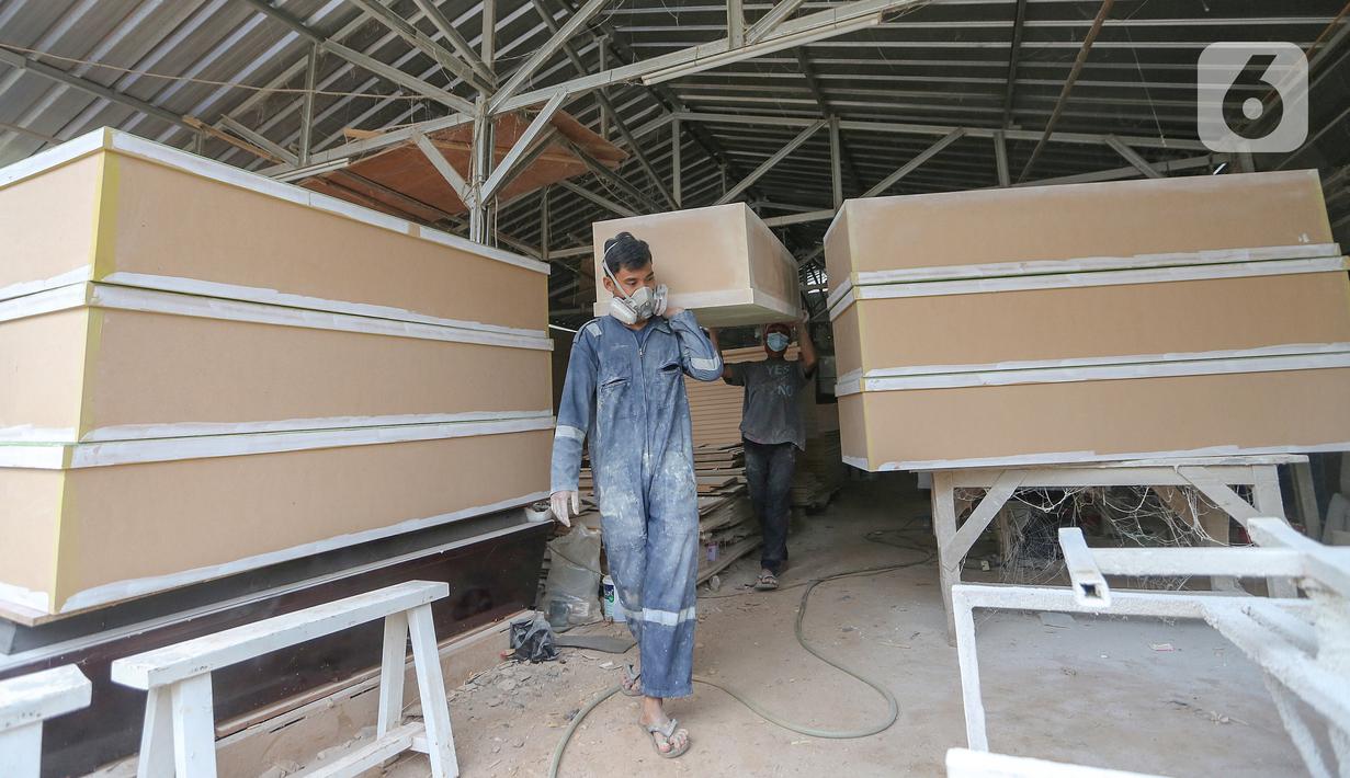 Pekerja membawa peti mati Covid-19 di Rawa Mekar Jaya, Serpong, Tangerang Selatan, Kamis (21/01/2021). Peti mati yang dijual dengan harga Rp 1 juta berbahan baku papan MDF didistribusi di wilayah Jabodetabek. (Liputan6.com/Fery Pradolo)