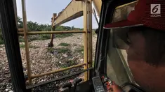 Petugas dari Dinas Lingkungan Hidup Kabupaten Bekasi menggunakan kendaraan alat berat mengeruk sampah yang memenuhi Kali Pisang Batu, Tarumajaya, Bekasi, Jawa Barat, Rabu (9/1). (Merdeka.com/Iqbal S. Nugroho)