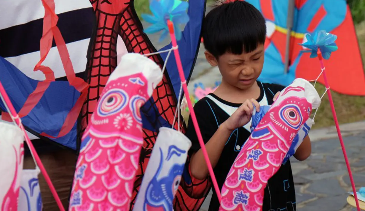 Seorang anak memeriksa layangannya saat mengikuti Festival Layang-Layang Internasional ke-16 di Baisha Bay, Taipei, Taiwan, 26 September 2015. (AFP PHOTO/Sam Yeh)