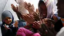 Seorang bayi tampak duduk di tengah imigran gelap perempuan yang tengah mengikuti misa di gereja darurat yang di dirikan di dekat kamp sementara mereka di sekitar pelabuhan Calais, Prancis, Minggu (2/8/2015). (REUTERS/Pascal Rossignol)