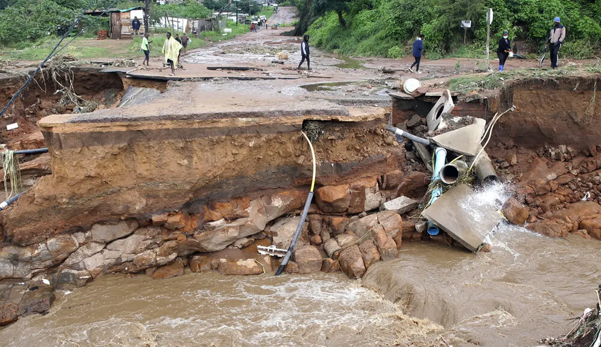 Orang-orang yang terlantar berdiri dekat jembatan yang hanyut di Ntuzuma, luar Durban, Afrika Selatan, 12 April 2022. Hujan berkepanjangan dan banjir di Provinsi KwaZulu-Natal Afrika Selatan telah merenggut puluhan nyawa, menurut pejabat setempat. (AP Photo)