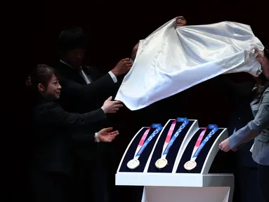 Medali Olimpiade Tokyo 2020 resmi diumumkan kepada publik saat seremoni untuk merayakan momen satu tahun jelang Olimpiade di Tokyo, Rabu (24/7/2019). Medali yang didesain Junichi Kawanishi itu berdiameter 85 mm dan dihiasi gambar dewi Yunani, Nike serta logo Olimpiade. (Behrouz MEHRI/AFP)