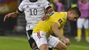 Pemain Jerman Serge Gnabry (kiri) berebut bola dengan pemain Rumania Razvan Marin pada pertandingan Grup J kualifikasi Piala Dunia Qatar 2022 di Hamburg, Jerman, 8 Oktober 2021. Jerman menang 2-1. (John MACDOUGALL/AFP)